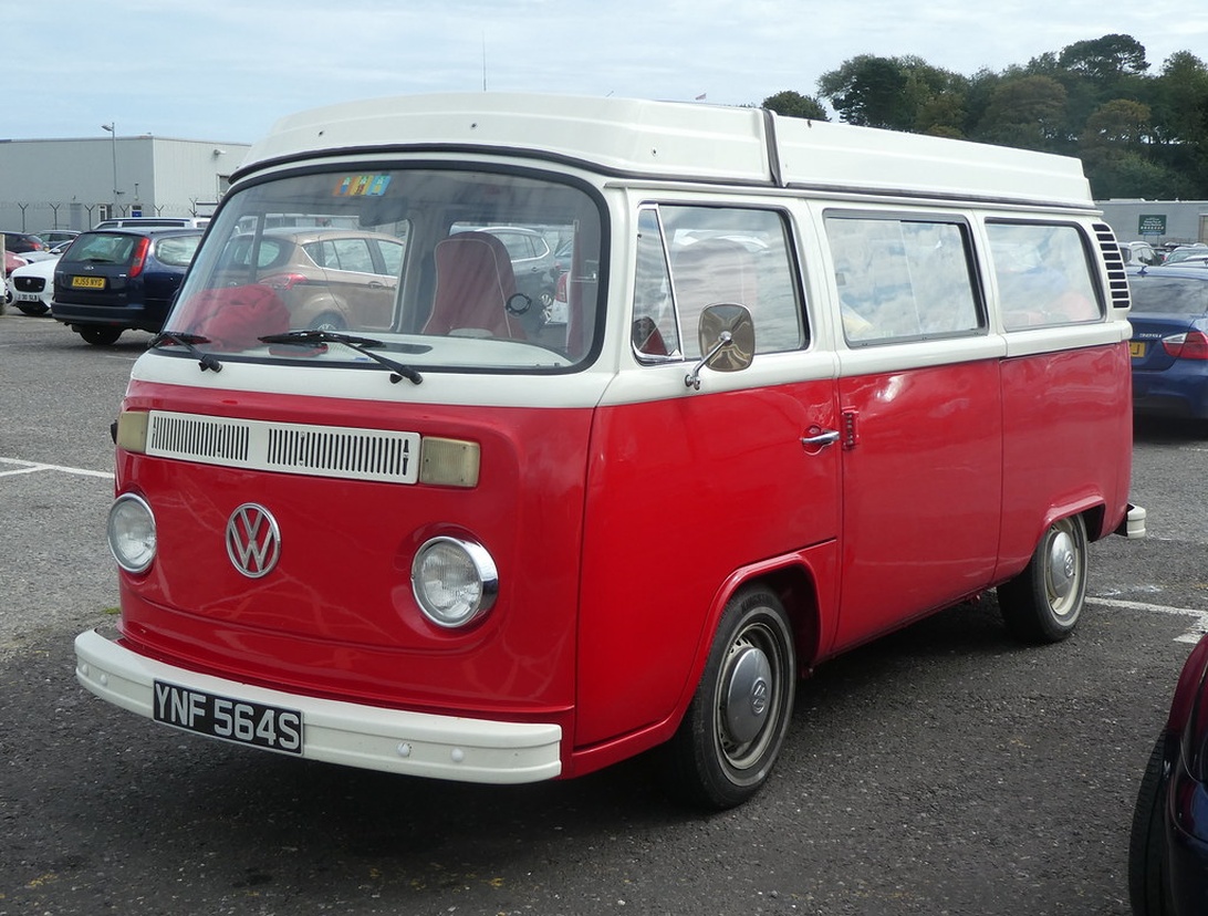 Een onberispelijke vintage Volkswagen T2 Bus in de klassieke rood-witte tweekleurige lak, geparkeerd op een parkeerplaats.